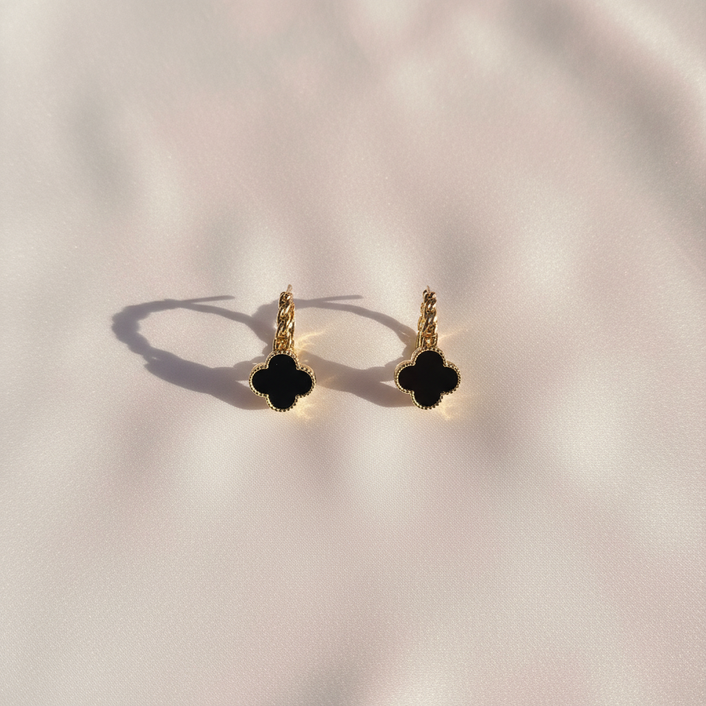 Flat lay aretes trébol dorado sobre seda